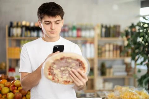 In shop guy scans QR code and take reading on pizza with prosciutto filling Photos