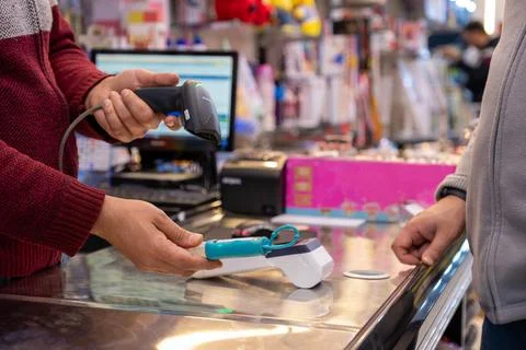 Shop man scan bar code on item selected by customer in gift shop with POS m.. Stock Photos