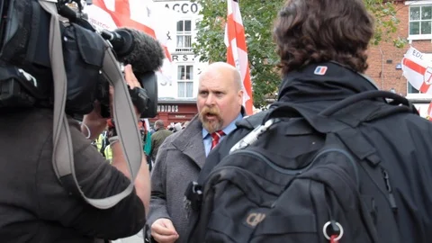 Shop owners look down on EDL mob whilst TV interviewee talks about the protest Stock Footage 114073418