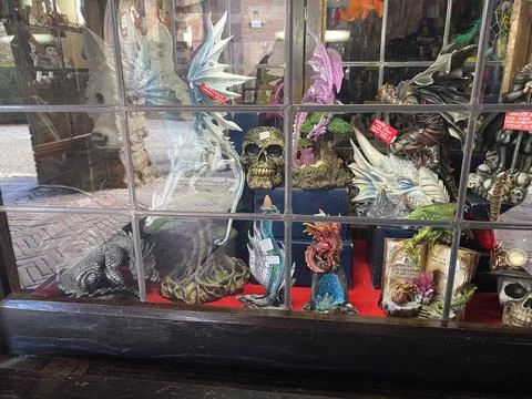 Shop window showcasing gothic and fantasy figurinesintricate dragons, skull.. Stock Photos