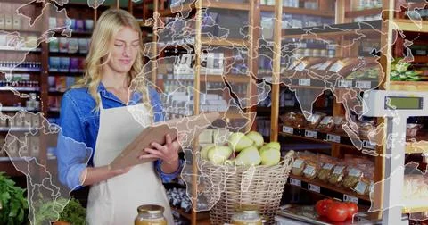 Shop worker scanning clipboard checking apples and scale for stock while map Stock Photos