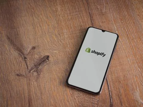 Shopify app launch screen on smartphone on wooden background Stock Photos