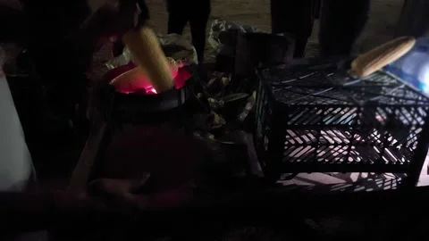 Shopkeeper heating corn cobs, snack on a small furnace with people standing Stock Footage 240553635