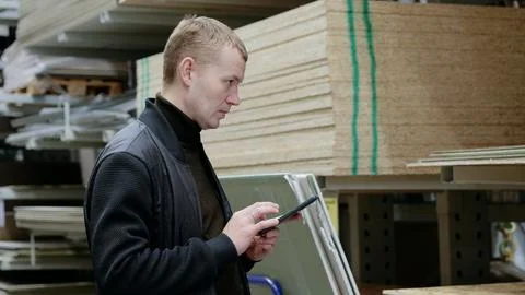 Shopper browsing building materials on a digital tablet, possibly checking .. 스톡 사진