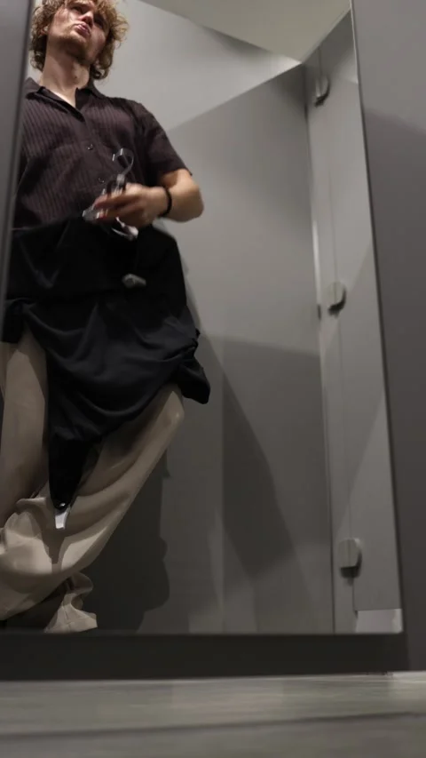 Shopper hesitates while deciding whether to buy clothing in a fitting room Stock Footage 344855776