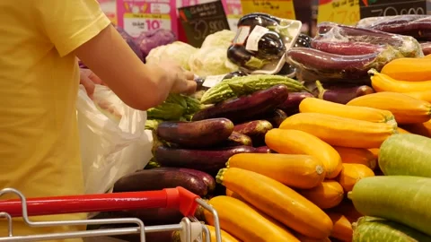 A shopper inspects a bitter melon, turning it over thoughtfully. The scene Stock Footage 307378643