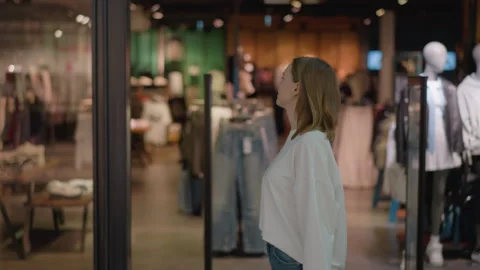 Shopper Looking at Clothing Store Display with Mannequins in Stylish Retail Vidéo 300096582