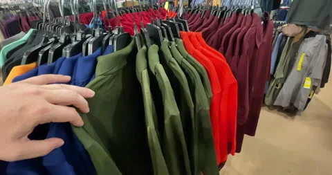 A shopper looks at shirts Vídeos de archivo 157376853