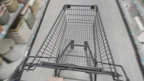 Shopper pushing empty cart between grocery store shelves, scanning product Stock Footage 315525630