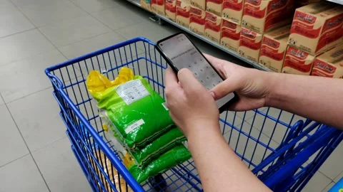 A shopper references a smartphone calculator while evaluating purchases Stock Footage 304070942