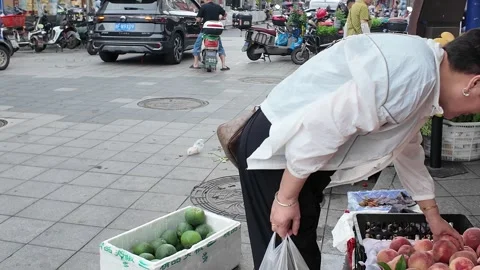 Shopper Selects Fresh Peaches at a Rainy Shanghai Morning Market Stock Footage 340176848