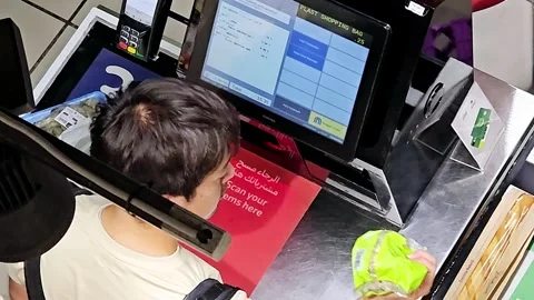 A shopper uses a self checkout machine, scanning an item. Stock Footage 312002649