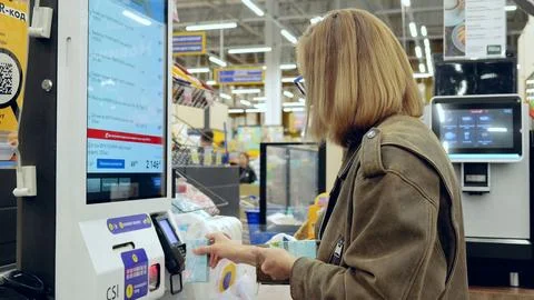 Shopper using self service checkout kiosk in modern supermarket, scanning Foto stock