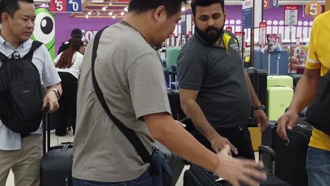 Shoppers browsing and selecting suitcases in the luggage section of Carrefour Video stock 312560459