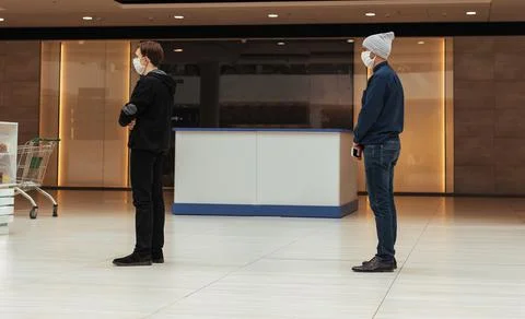 Shoppers in protective masks standing in a queue in a supermarket Stock Photos