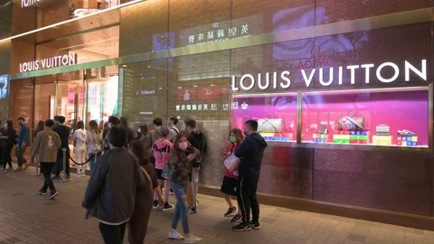 Pedestrians walk past the French luxury fashion brand Louis