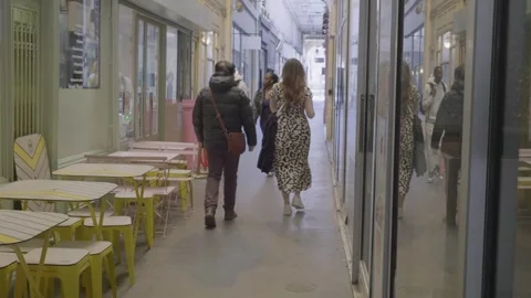 Shoppers walking through a Parisian arcade with reflections on glass surfaces Stock Footage 305756828