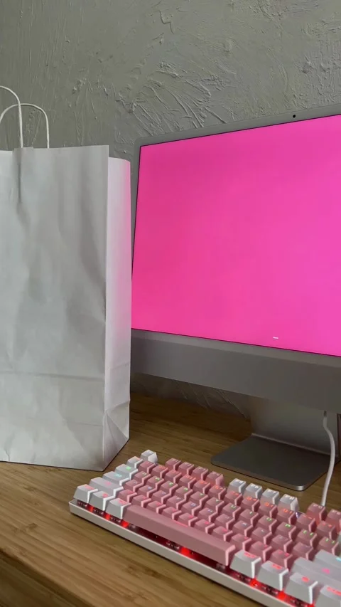 Shopping bag next to computer with pink screen display Stockbeeldmateriaal 331770957
