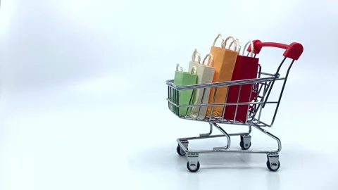 Shopping bags jumping into Shopping cart in stop motion on white background Stock Footage