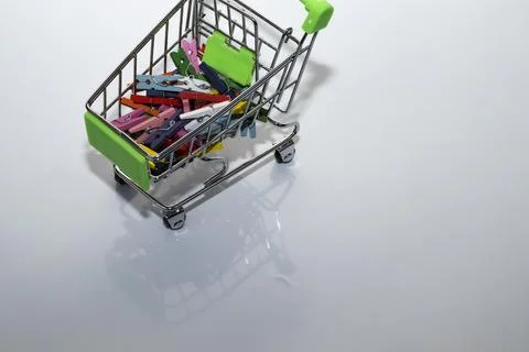 Shopping basket multi-colored mini clothespins on a white background Stock Photos