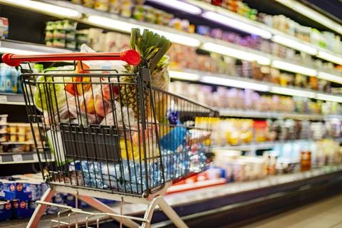 A shopping cart with grocery products in a supermarket Stock Photos
