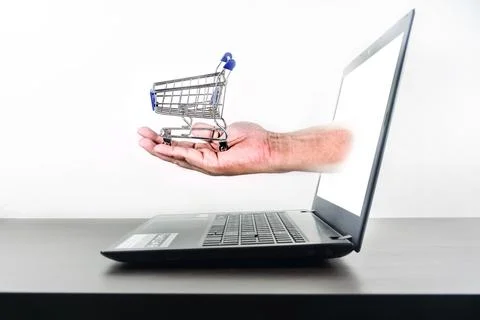 Shopping cart in hand Computer notebook blank screen on wood table 스톡 사진