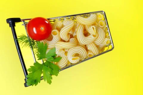 A shopping cart with Italian pasta, ripe cherry tomatoes, parsley and dill. Stock Photos