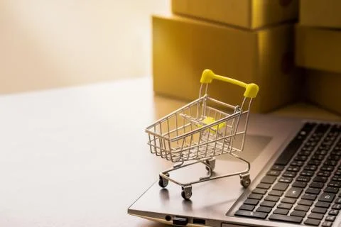 Shopping cart or trolley  on a notebook computer placed in front of the parce Stock Photos