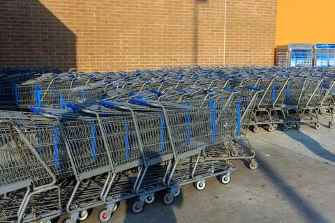 Shopping carts lined up outside store in daylight near brick wall Stock Photos