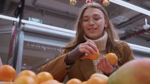 Shopping for citrus and mango in festive setting. Joyful shopper examines fresh Stock Footage 335956971