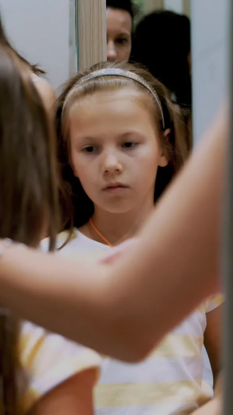 Shopping. in fitting room of large store, pretty, serious girl, a kid tries on Stock Footage 314659031
