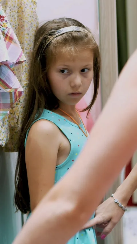 Shopping. in fitting room of large store, pretty, serious girl, a kid tries on Stock Footage 314980880
