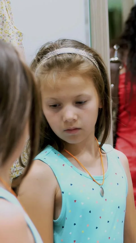 Shopping. in fitting room of large store, pretty, serious girl, a kid tries on Stock Footage 315365290