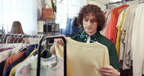 Shopping, rack and man in store with clothes, outfit search and decision with Stock Footage 345658161