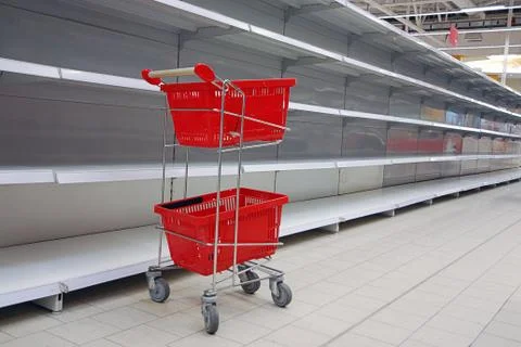 Shopping trolley with empty baskets by empty shelves in supermarket Stock-Fotos