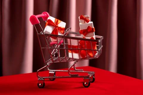 Shopping trolley full of present boxes on red  background. Stock Photos