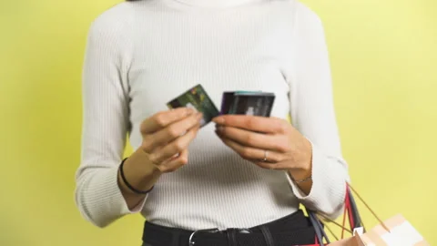 Shopping woman looking at big stack of credit cards and carrying colorful shoppi Stock Footage 146970689