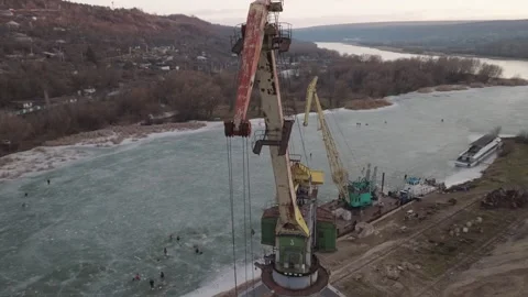 Shore-based rail-mounted portal crane in drone view beside a partially frozen Stock Footage 345369511