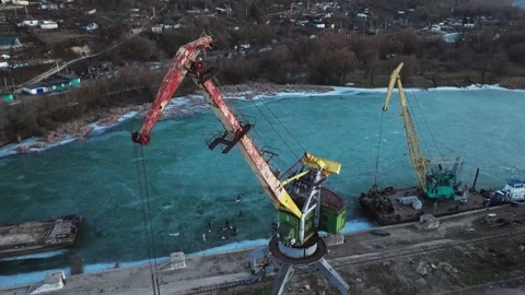 Shore-based rail-mounted portal crane from a drone above a partially frozen Stock Footage 345369771