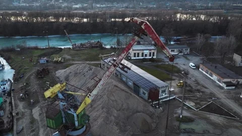 Shore-based rail-mounted portal crane in a drone view over an industrial river Stock Footage 345369842