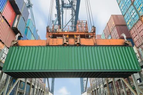 Shore crane loading containers in freight ship Stock Photos