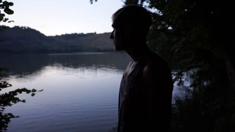 The shore of the river after sunset, a young guy stands on the riverbank Stock Footage 114631330