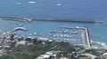 Shore with small harbor and docked boats separated from choppy sea by breakwater HD Footage