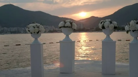 On shore there are columns with flowers on background of summer sunset. Video stock 82355992
