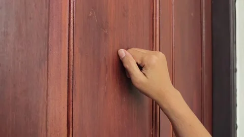 Short clip of female hand making a knocking gesture on a brown timber door, sile Stock Footage 339744299