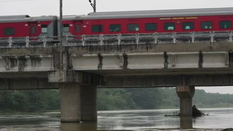 A short clip of a red long train moving on the bridge over water Stock Footage 225739120