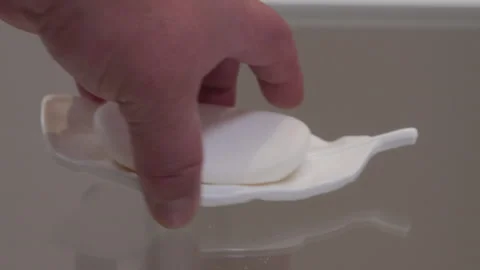 Short Dull Clack as Hand Places White Soap Dish with Soap on Glass Stock Footage 321267570