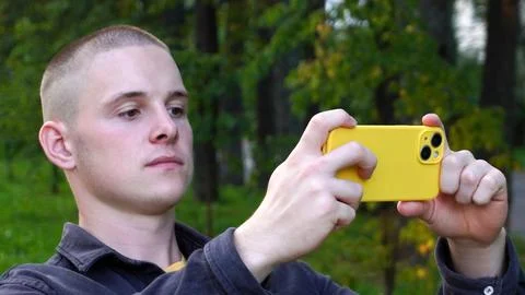 Short-haired athletic guy takes a selfie on a smartphone in a yellow case Foto stock