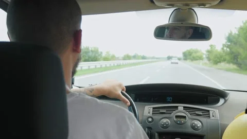 A short-haired, bearded man drives a car along a highway outside the city. A man Video stock 221828597