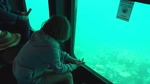 Short-haired girl is looking through the underwater window on the submarine boat Stock Footage 233614141